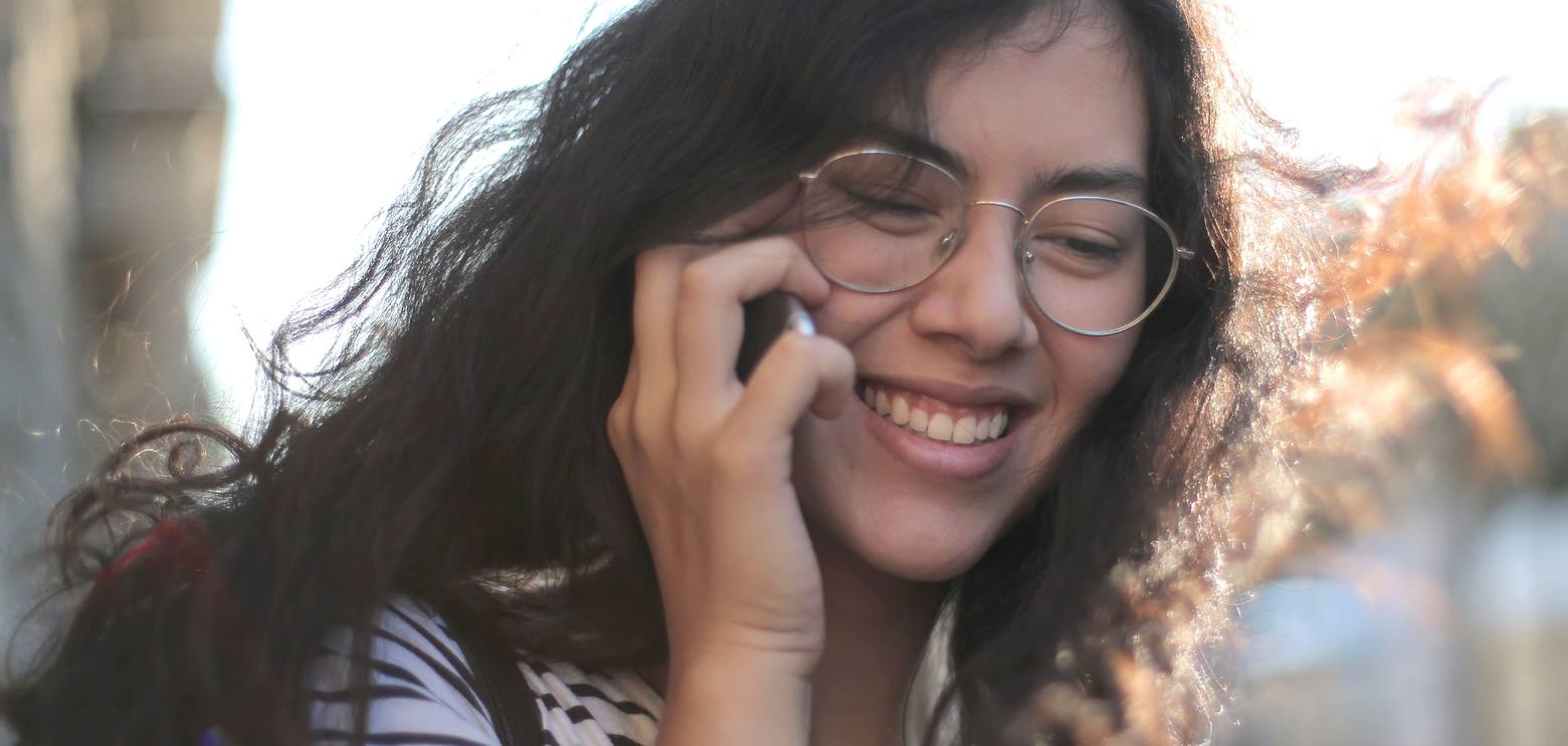 Une jeune femme souriante en train de téléphoner dans la rue