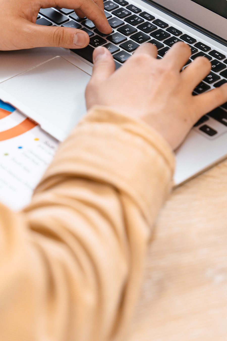 Deux mains sur le clavier d’un ordinateur portable posé sur une table